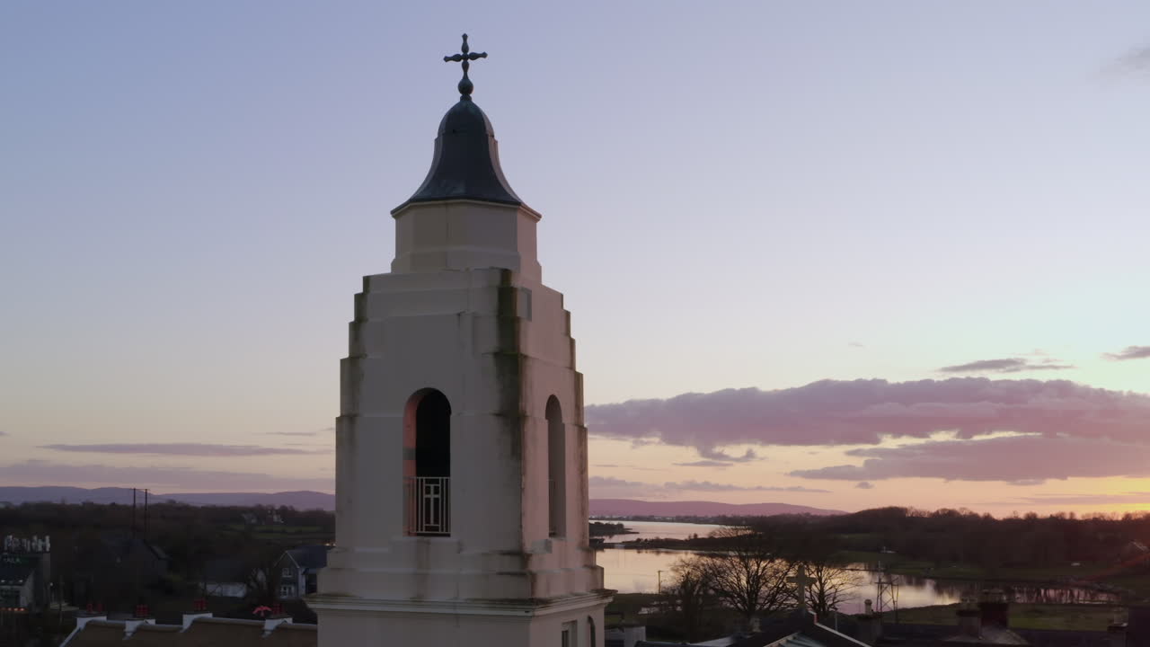 Church tower in Clarinbridge silhouetted by dramatic sunset with pink and purple evening tones