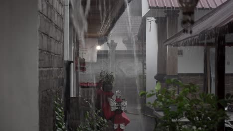 monsoon rainstorm in bali village, strong rain falling on balinese house yard