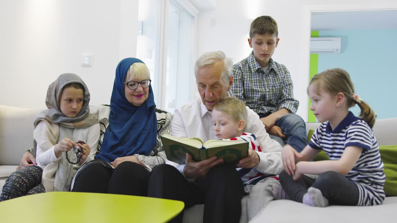 Keluarga Muslim lintas generasi, kakek-nenek membaca Al-Qur'an bersama cucu di rumah.