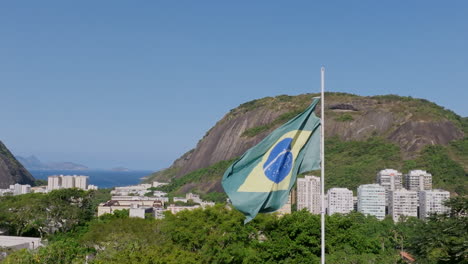 Imágenes-Aéreas-En-Cámara-Súper-Lenta-Girando-Alrededor-De-La-Bandera-De-Brasil-Moviéndose-En-El-Viento-En-El-Parque-Yitzhak-Rabin-En-Río-De-Janeiro