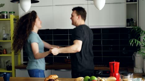 cheerful and attractive young couple in love dancing together rocknroll dance in the kitchen at home on holidays