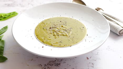 creamy soup with green pea in a ceramic white plate