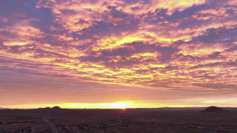 mojave desert at sunrise with vivid orange and purple clouds, aerial view, timelapse