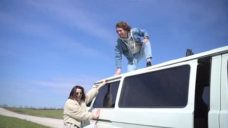 young boy helps his girl friend onto the roof of the caravan.