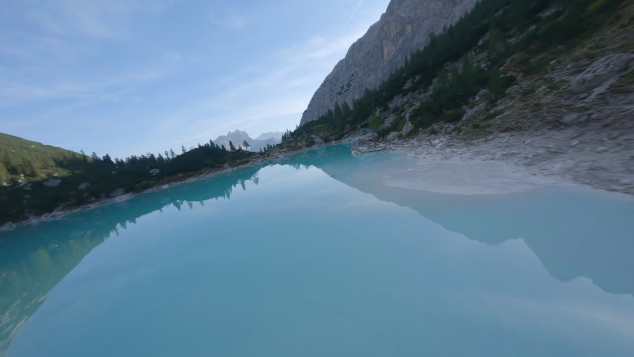 dron fpv volando sobre un pequeño lago glacial turquesa en la temporada de verano, montañas dolomitas, italia