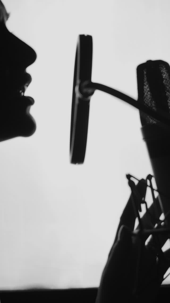 Woman singing in the recording studio. Profile of a woman with a beautiful face and lips. Black and White Vertical video