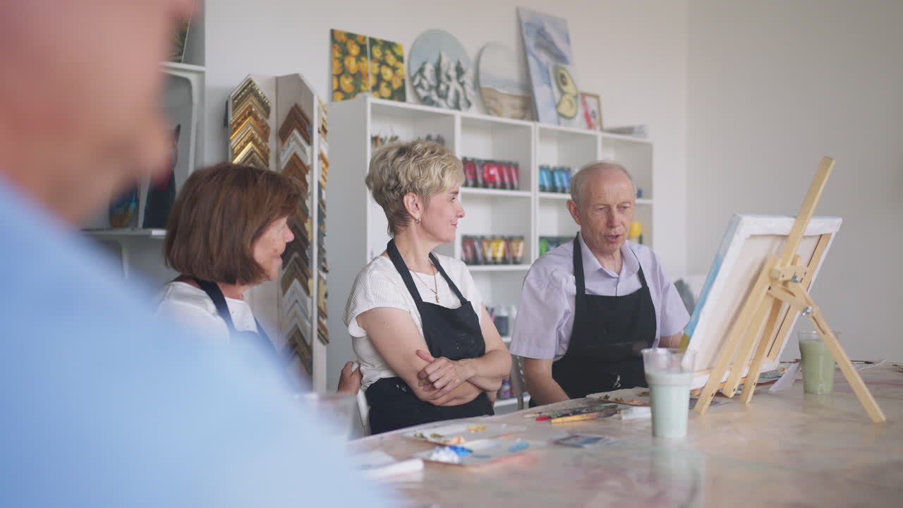 노인 남녀들이 그림 수업에 대한 인상을 공유합니다. 노인들의 감정은 함께 이야기합니다. 노인 친구들을 위한 활동