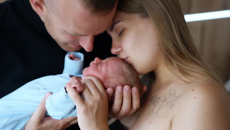 happy portrait of family of three. first time parents with their newborn boy in hands. close up.