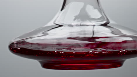 closeup decanter shaking red wine in slow motion. rose drink moving inside bowl