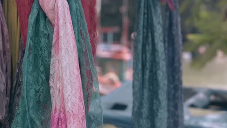 bright colored lacy scarfs hang on shop show window on day