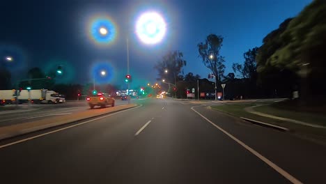 Rear-facing-night-driving-point-of-view-POV-for-interior-car-scene-green-screen-replacement---quiet-and-well-lit-dua-carriageway-intersection-with-traffic-lights