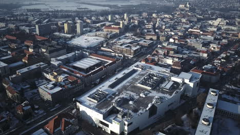 Volando-Sobre-Un-Gran-Centro-Comercial-Hacia-La-Intersección-Principal-En-La-Ciudad-De-Nitra,-Invierno,-Toma-Aérea,-Eslovaquia