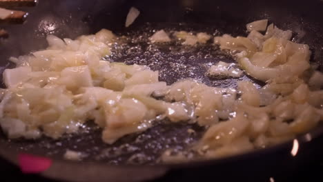 diced raw chicken breast added to sauteed onions in pan on hot stove