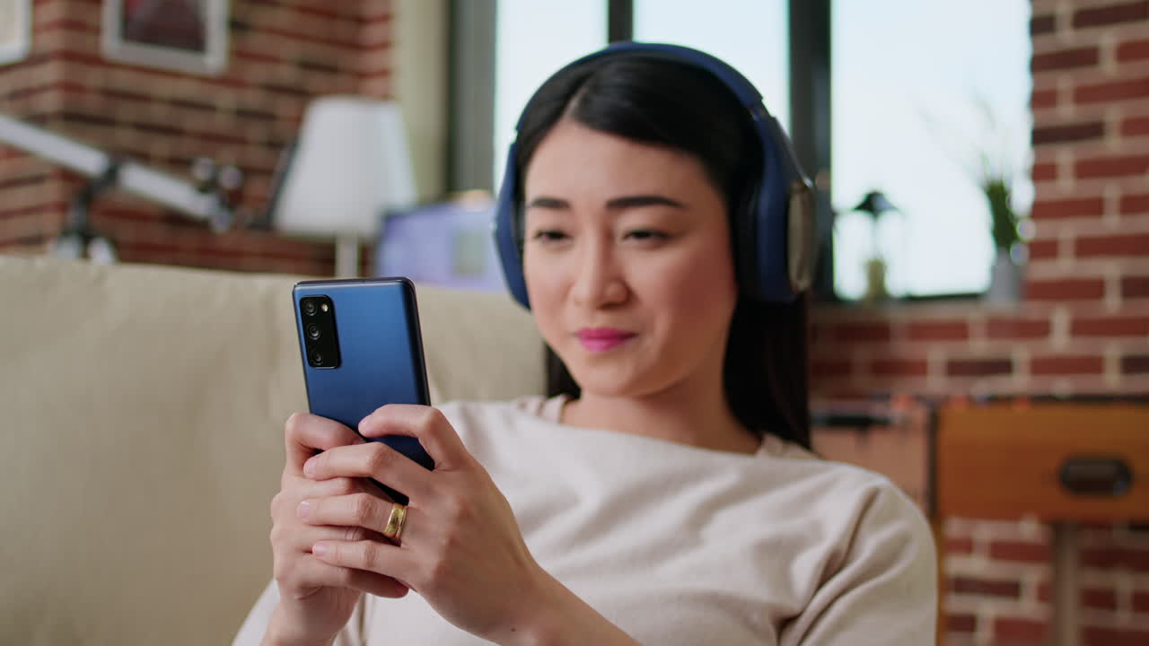Woman with Headphones Using Smartphone at Home