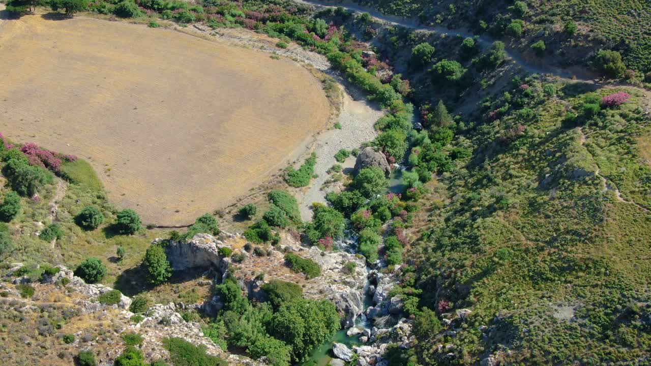 antena sobre las montañas verdes y un pequeño arroyo de agua que se abre paso entre ellas, en un día soleado