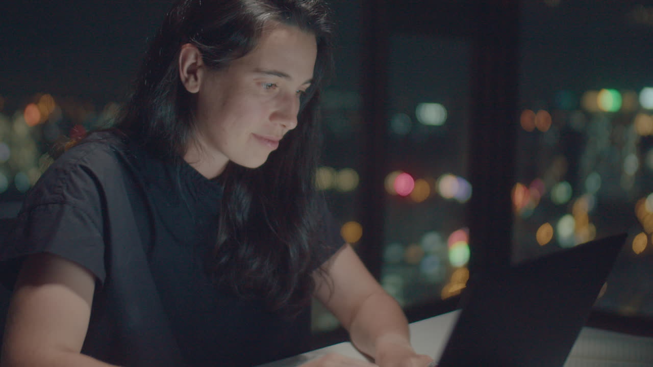 European woman writer typing poetry illuminated the screen