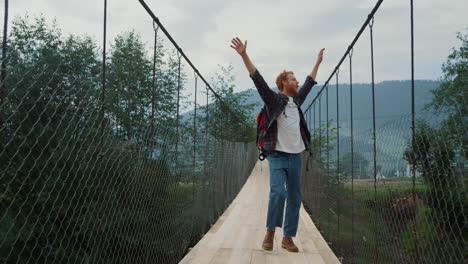 carefree guy explore nature on mountains river bridge. excited hiker enjoy walk.