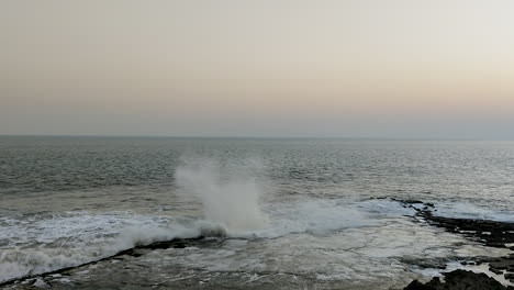 Experience-the-beauty-of-a-slow-motion-shot-capturing-water-splashing-up-as-waves-crash-against-a-rocky-shore,-creating-a-mesmerising-display-of-coastal-dynamics-and-natural-elegance