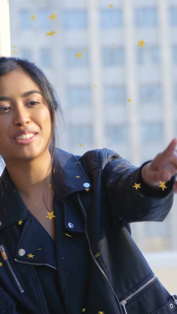 Vídeo vertical: Mulher estendendo o braço após sorrir, oferecendo algo fora da tela para moda, com estrelas ao redor dela.