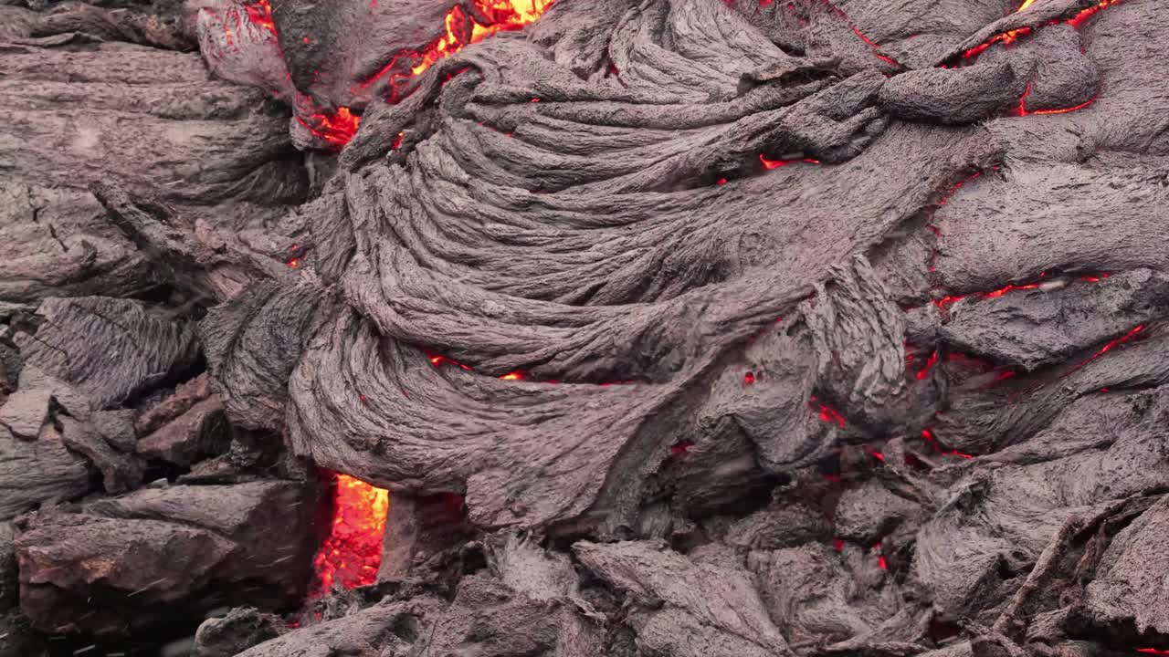 nevando sobre magma brillante y roca volcánica, en islandia - tiro estático, cerrado