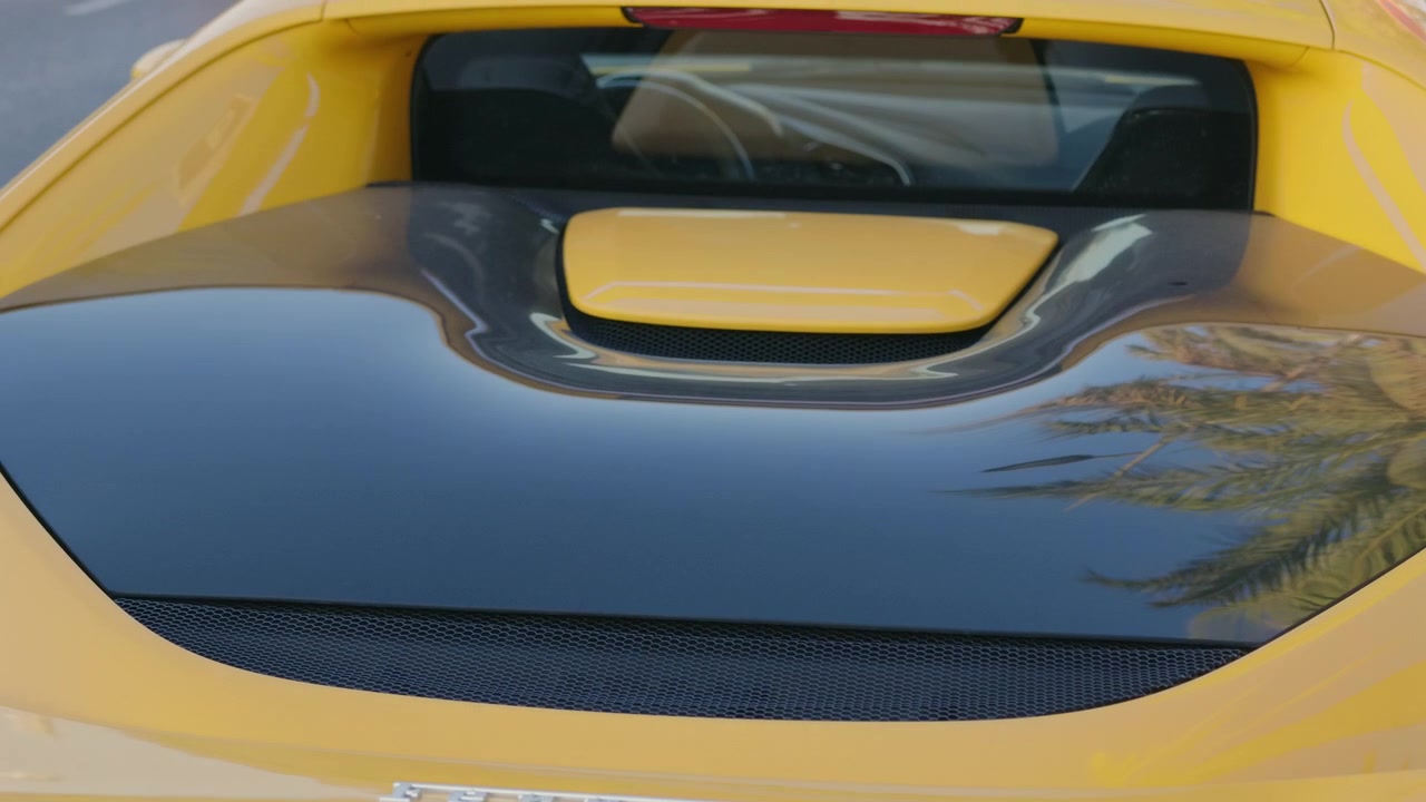 Nahaufnahme der hinteren Motorabdeckung und der Gitterlüftungen eines gelben Sportwagens, die eine Palme spiegeln, Côte d'Azur, Frankreich