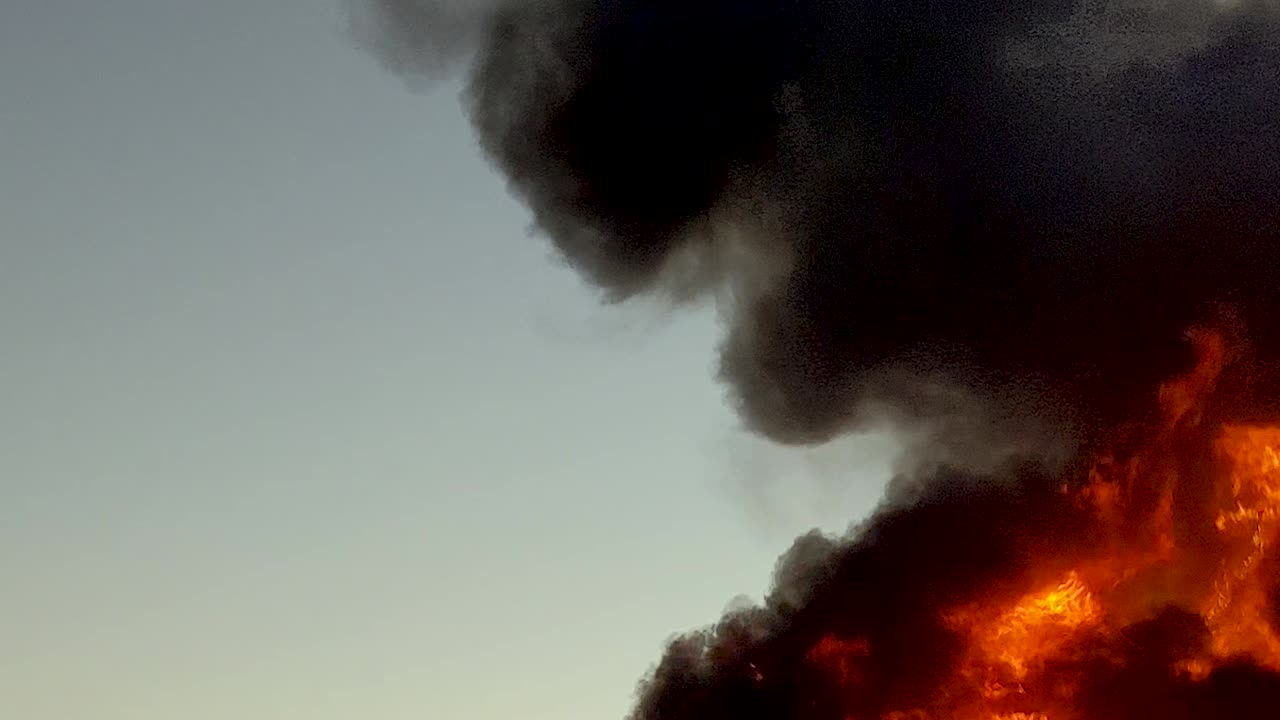 거대하고 위험한 맹렬한 불이 빠르게 타면서 짙은 검은 불꽃을 하늘로 치솟게 합니다.