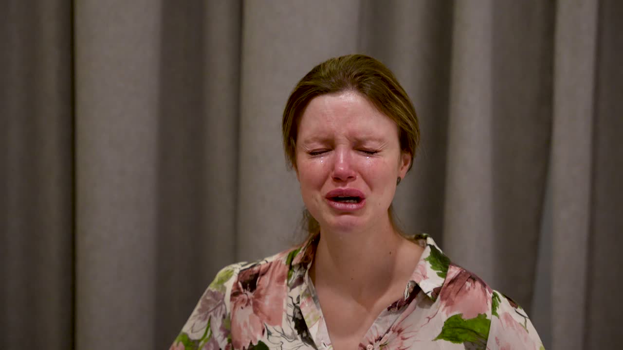 A young woman cries in distress while speaking on camera, showing sadness, emotion, vulnerability, mental strain and personal struggle in a dramatic emotional candid moment