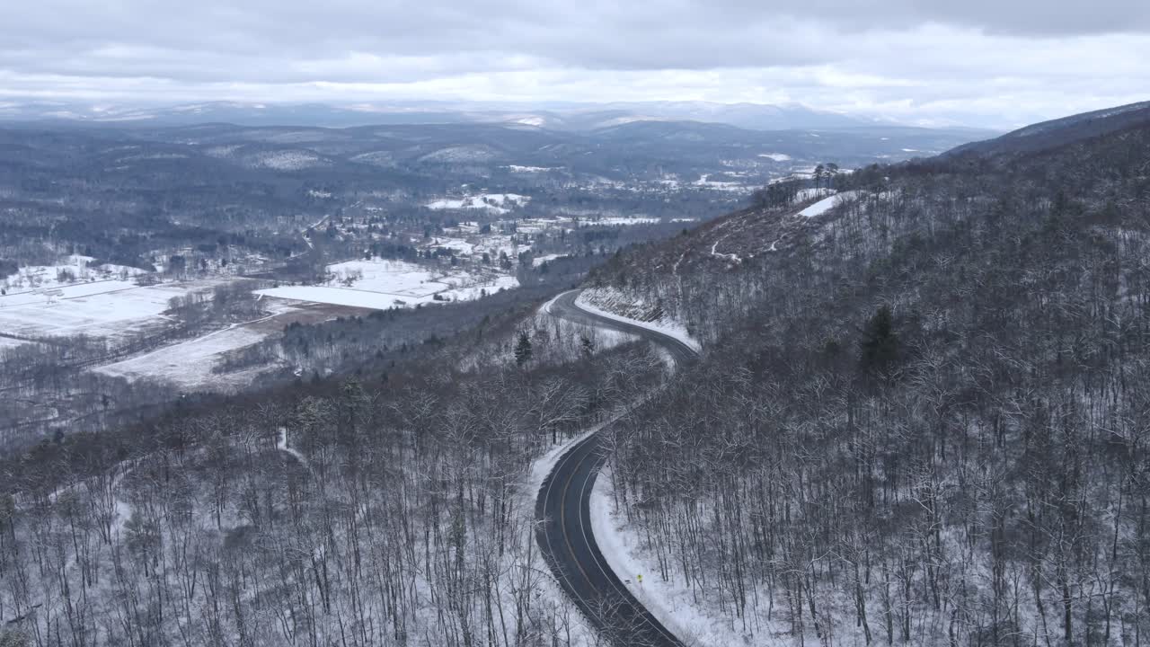 광대한 눈 덮인 산과 멀리 눈 덮인 산이 있는 눈 덮인 산의 경치 좋은 고속도로의 공중 드론 영상