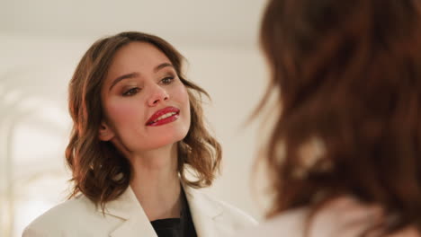Positive-woman-with-red-lipstick-on-lips-looks-in-mirror