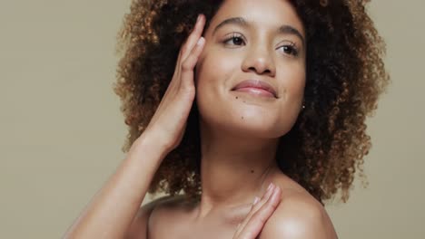 happy biracial woman with dark curly hair on beige background, slow motion
