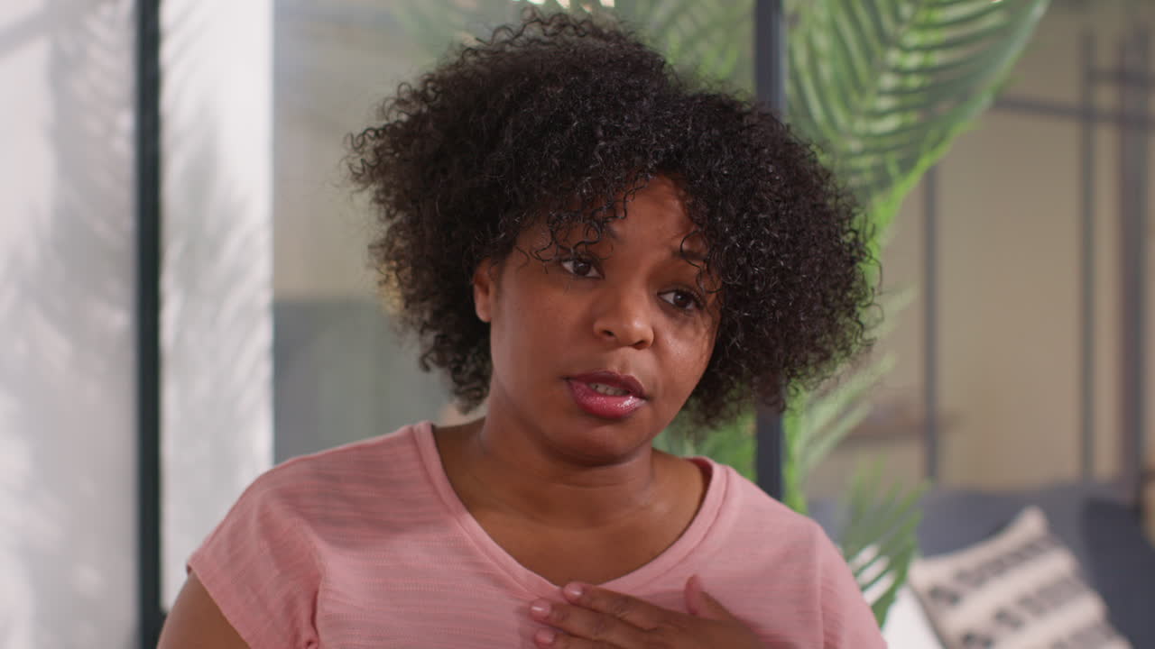 Woman Wearing Pink Breast Cancer Awareness Ribbon Talking At Meeting Of Therapy Support Group For Cancer Treatment Patients
