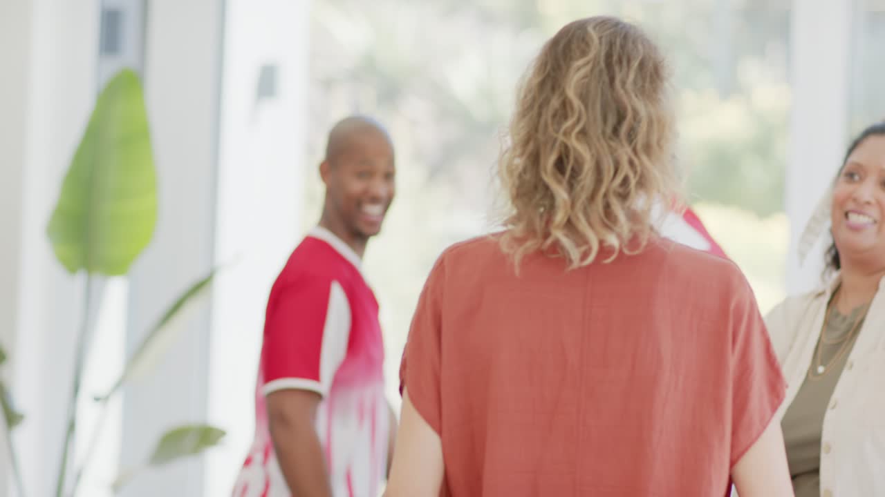 Four friends entering home entryway after door opening, holding soccer ball and flag, celebrating