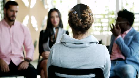 vista posterior de una mujer joven con trenza sentada en una silla