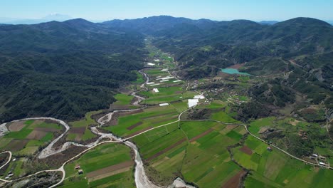 Ruhiger-Fluss,-Der-Sich-Durch-Eine-Atemberaubende-Landschaft-Schlängelt:-Tal-Mit-Grünen-Parzellen,-Frühlingsfeldern-Und-Bezaubernder-Dorflandschaft-In-Albanien