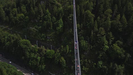 Vista-Aérea-Del-Puente-Colgante-Peatonal-Más-Largo-Del-Mundo,-Que-Conecta-El-Castillo-De-Ehrenberg-Y-Fort-Claudia-En-Austria,-Sobre-Una-Carretera-Muy-Transitada-Y-Rodeado-Por-Un-Bosque-De-árboles.