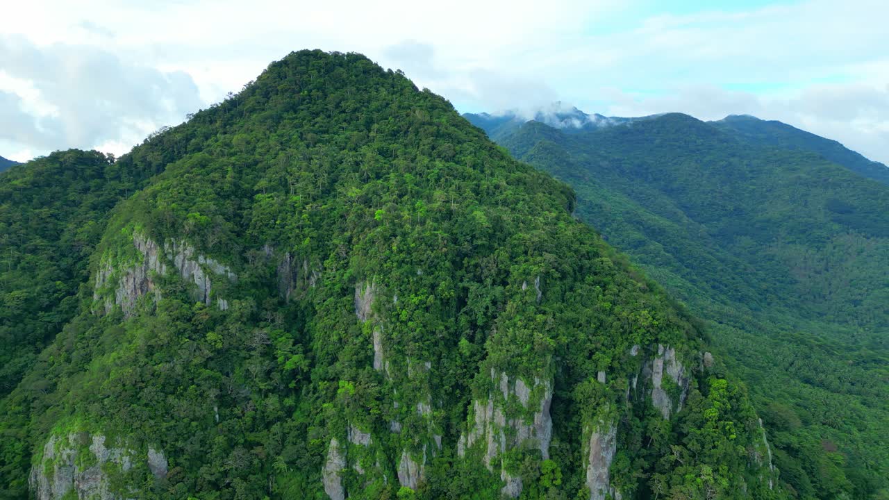 Pandangan udara sisi bawah dari puncak batu kapur bergerigi dan hutan tropis lebat Tulay na Busog di Lobo, Batangas, di bawah langit cerah dan jernih