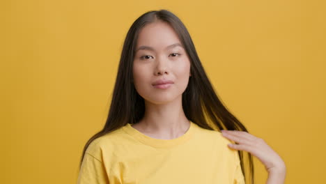 young asian woman posing and smiling on yellow background