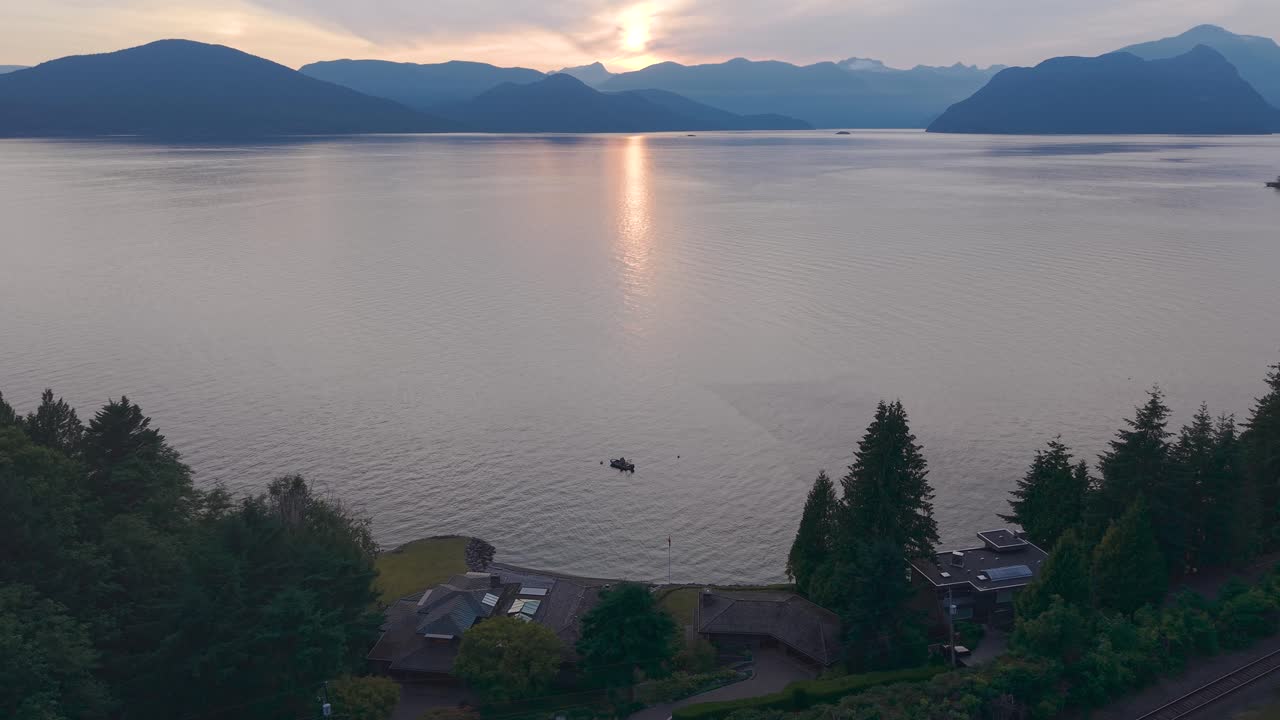 an aerial drone shot of a sunset on Gambier Island from the views of a the coast of Lions Bay with luxury properties on the bottom