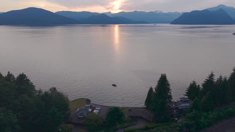 an aerial drone shot of a sunset on gambier island from the views of a the coast of lions bay with luxury properties on the bottom