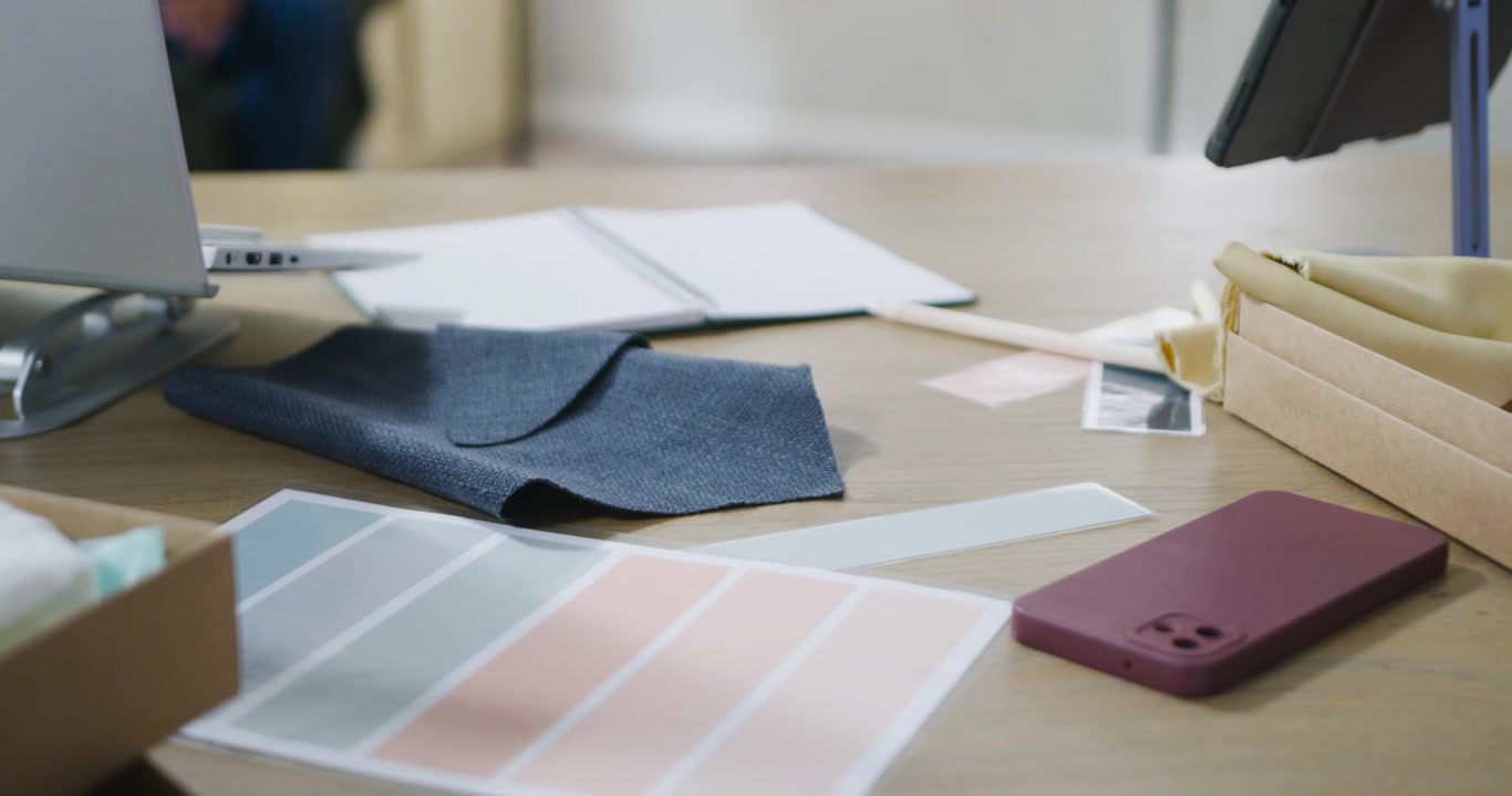 Scrivania da designer con campioni di tessuto e tavolozza di colori.