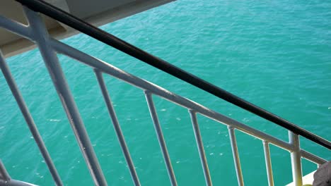 view of the blue waters of the ionian sea through the protective railings of a sailing ferry