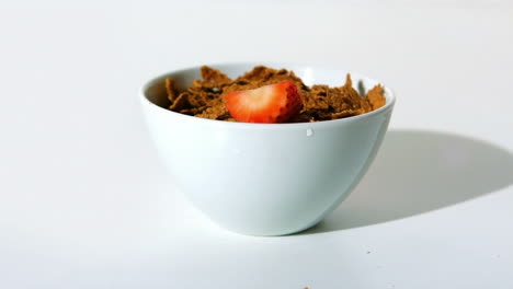 fresa cayendo en un cuenco de cereales de trigo