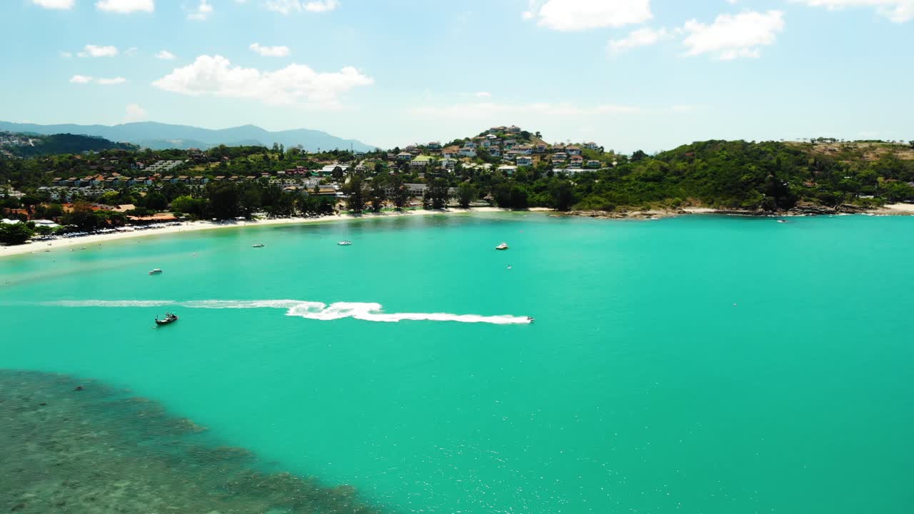 A follow-through drone aerial shot of a jetski speeding off to the open waters of Choeng Mon Beach resort in Koh Samui Island in Surat Thani province in Thailand