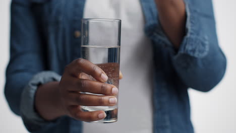 person holding a glass of water with medication