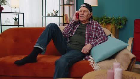 happy stylish senior grandfather man holding smartphone talking with friends at home conversation