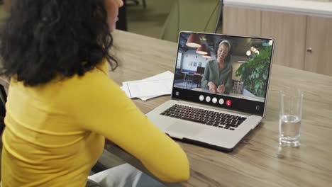 Mujer-Birracial-Usando-Una-Computadora-Portátil-Para-Videollamada,-Con-Un-Colega-De-Negocios-En-La-Pantalla