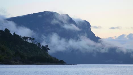 A-mesmerizing-view-of-clouds-gracefully-drifting-beneath-a-towering-mountain,-revealing-the-dynamic-beauty-of-nature's-dance-in-the-sky