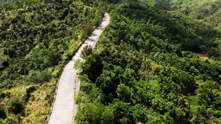 Veduta aerea di una strada tortuosa attraverso colline verdi ad Aguilar, Pangasinan, in una giornata di sole.