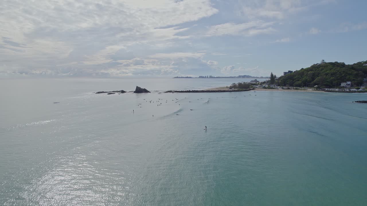 여름에 상징적인 암석이 있는 커럼빈 해변의 서퍼 - 퀸즐랜드 골드 코스트에서 서핑