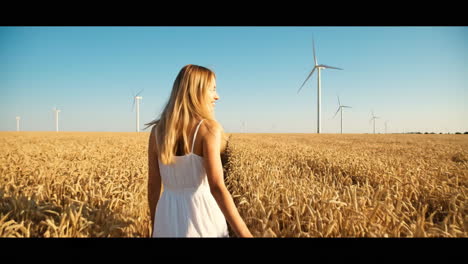 woman in a wheat field with wind turbines